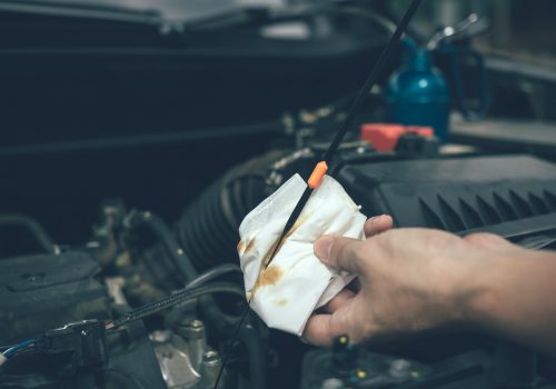 Car mechanic is checking the engine oil of the car using a steel and cleaner by tissue. Car mechanic is checking the engine oil of the car using a steel and cleaner by tissue.